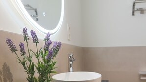 A bathroom with a round sink, a potted lavender plant, a mirror, and a toilet. - Dorinda Rooms  (Alicante)