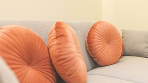 A grey sofa with three orange cushions. - Dorinda Rooms  (Alicante)