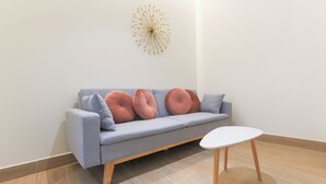 A modern living room with a grey sofa, wooden legs, and a white coffee table. - Dorinda Rooms  (Alicante)