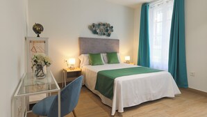 A bedroom with a bed, bedside tables, a desk, and a chair. - Dorinda Rooms  (Alicante)