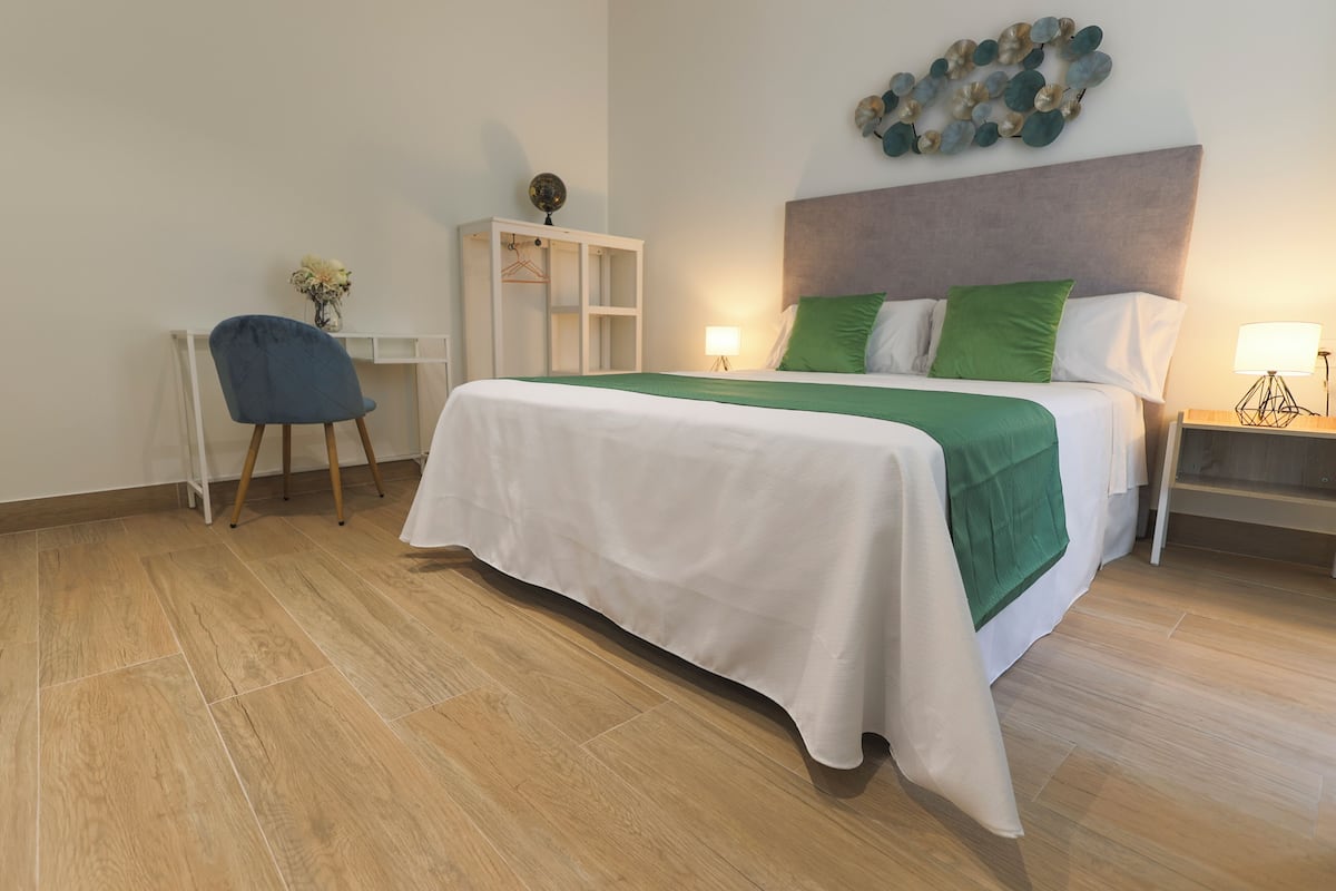 Ein ordentlich eingerichtetes Hotelzimmer mit Bett, Nachttischen, Schreibtisch und Stuhl.