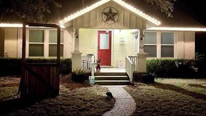 Una casa con porche, puerta roja y un símbolo de estrella en la fachada.
