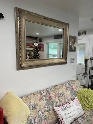 Relax in this inviting living room with a floral-patterned sofa, ornate mirror, and cozy table with a lamp.