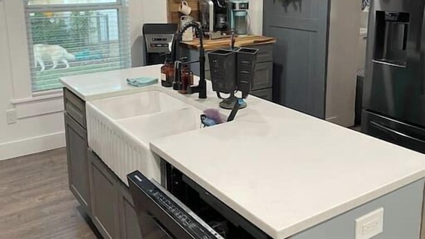 Una cocina moderna con una isla central, electrodomésticos de acero inoxidable e iluminación colgante.