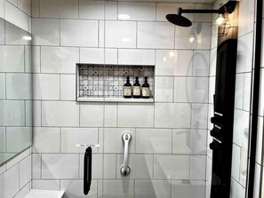 Enjoy a clean and functional bathroom with a shower area, handheld showerhead, and shelf.