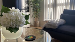 Una sala de estar con una mesa baja de vidrio, una planta en maceta, un sofá y un televisor.