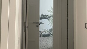 A hallway leading to a door with a view of a water body and greenery. - chiesa russa (Bari)