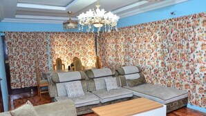 A living room with a sectional sofa, a wooden coffee table, and a chandelier.