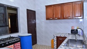 A compact kitchen with a gas stove, a microwave, and wooden cabinets.
