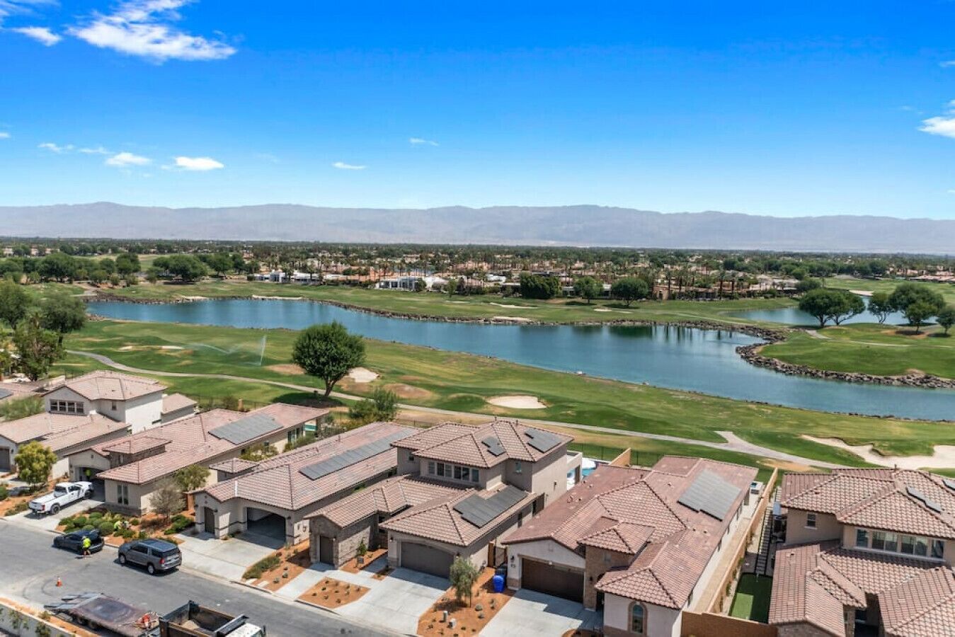 A residential area with houses, a golf course, and a lake.