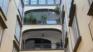Un edificio de varios pisos con balcones, plantas en macetas y una zona de recepción.