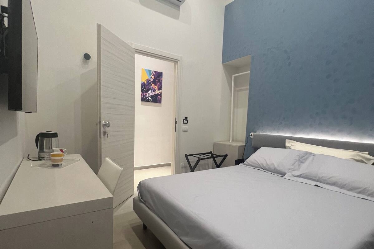 A modern hotel room with a bed, a desk, and a coffee maker.