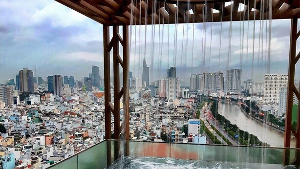 A person in a hot tub overlooking a cityscape with a river and buildings. - The Rixx D1 Mension (Ho Chi Minh City)