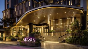 A modern hotel entrance with a curved canopy, a staircase, and a neon sign. - The Rixx D1 Mension (Ho Chi Minh City)