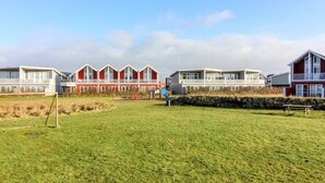 A row of red and white vacation homes with a grassy field in the foreground.