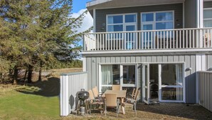 A two-story building with a balcony, outdoor seating, and a grill.