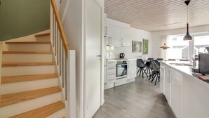 A modern kitchen with white cabinets, a built-in oven, and a dining area with black chairs.