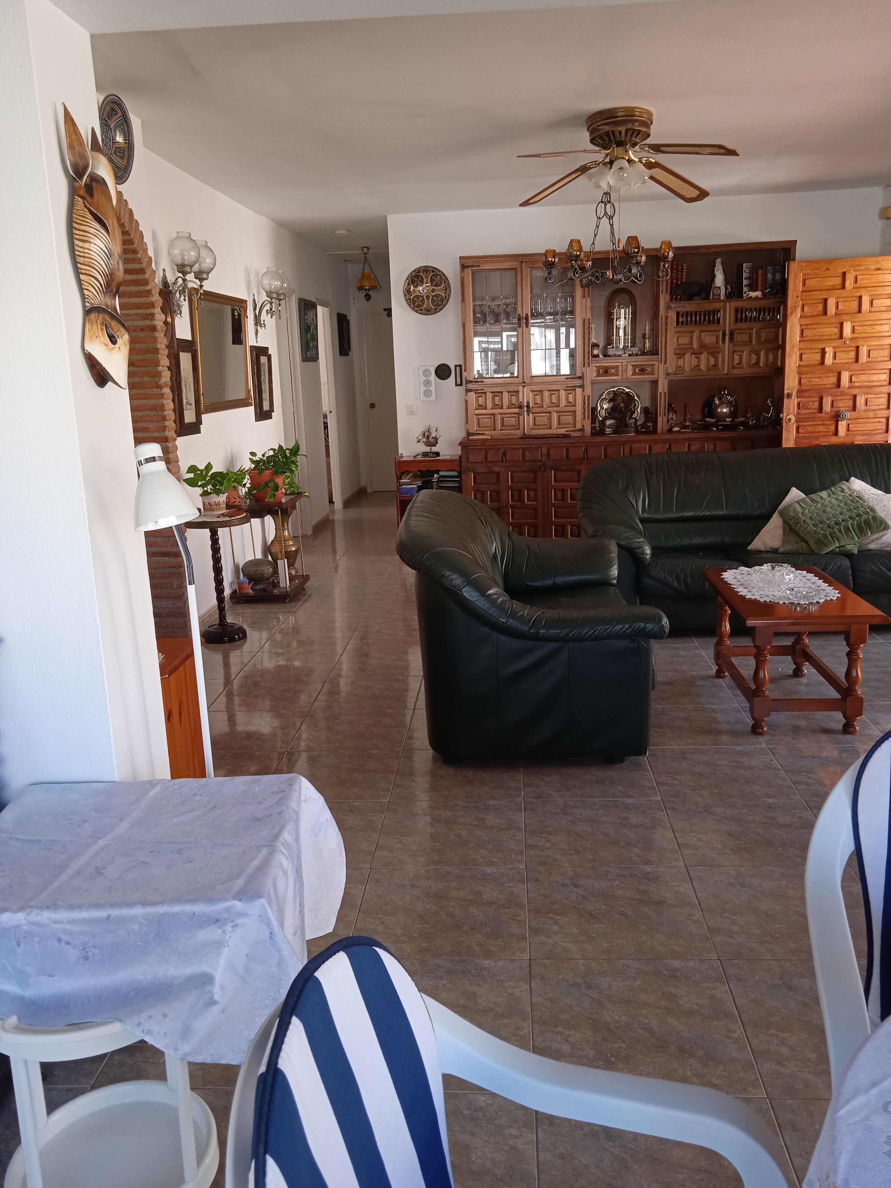 Un salón amplio con un sofá verde, un mueble de madera y un ventilador de techo.