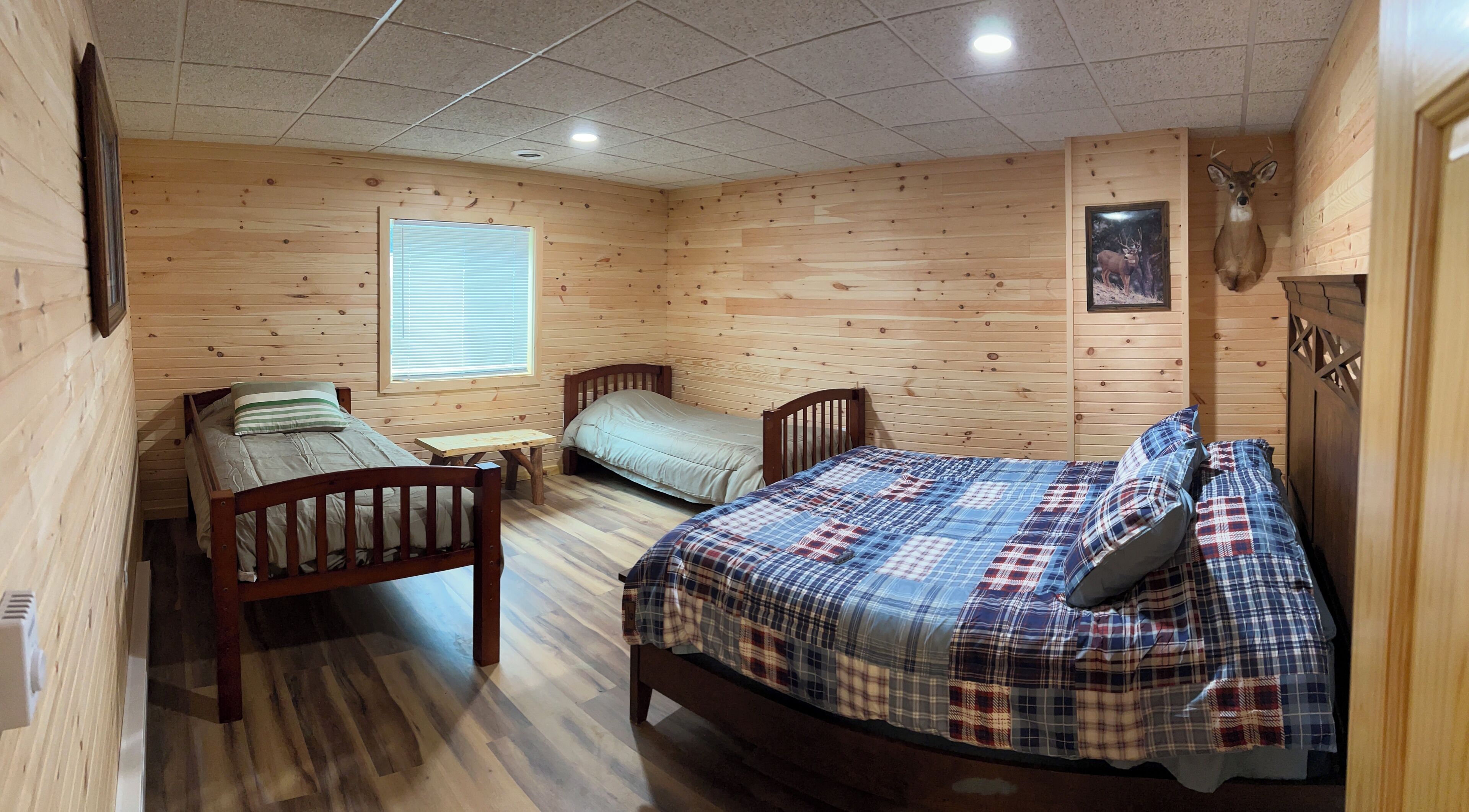 A wooden cabin-style room with two single beds, a small table, and a window.