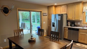 Una cocina moderna con armarios de madera, un refrigerador de acero inoxidable y un comedor con mesa y sillas de madera.