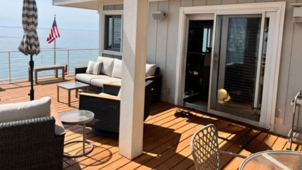 A deck with outdoor furniture, including a sofa and chairs, and a glass door leading to an interior space. - Superbly located beachfront house in Grand Haven! Just minutes from Downtown (Spring Lake)