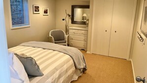 A bedroom with a bed, a dresser, a chair, a closet, and a window with blinds. - Superbly located beachfront house in Grand Haven! Just minutes from Downtown (Spring Lake)