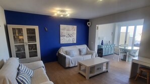 Uma sala de estar com parede azul decorativa, um conjunto de sofá, uma mesa de centro e um armário.