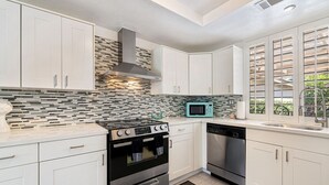 Une cuisine moderne avec des meubles blancs, une cuisinière noire, un four à micro-ondes et un lave-vaisselle.