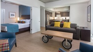 A modern hotel room with a bed, a sofa, a dining table, and a kitchenette in the background. - Studio unit/Austin - Full Kitchen, W/D, Rooftop Pool, & More! (Austin)
