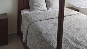 A bed with a canopy, patterned bedding, and a wooden headboard. - Deux-Palmes-Kribi, close to the beach (200m), comfortable and family-friendly (Kribi)
