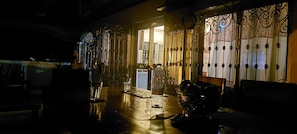 Une pièce faiblement éclairée, ornée de rampes de fer forgé, avec un sol mouillé et une bouteille de Super 800 posée sur la table.