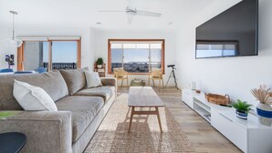 A modern living room with a sofa, coffee table, and a large TV mounted on the wall.