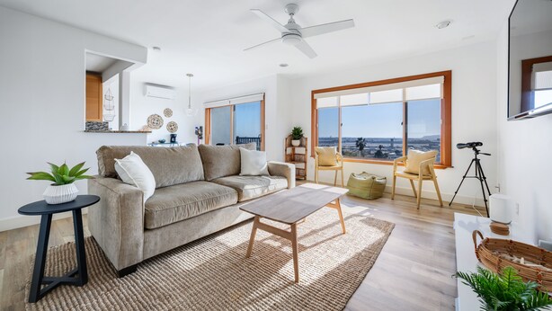 A modern living room with a sofa, coffee table, and a view of the city.