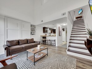 Un salon moderne avec un canapé en cuir marron, une table basse en bois et un tapis à motifs.