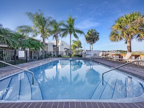 Une piscine à l’eau d’un bleu limpide, entourée d’une terrasse en briques.