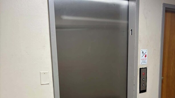 Un ascensor con un botón de alarma contra incendios y un número de puerta.