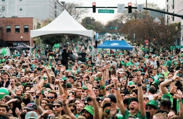 A crowded outdoor event with a tent and a street sign.