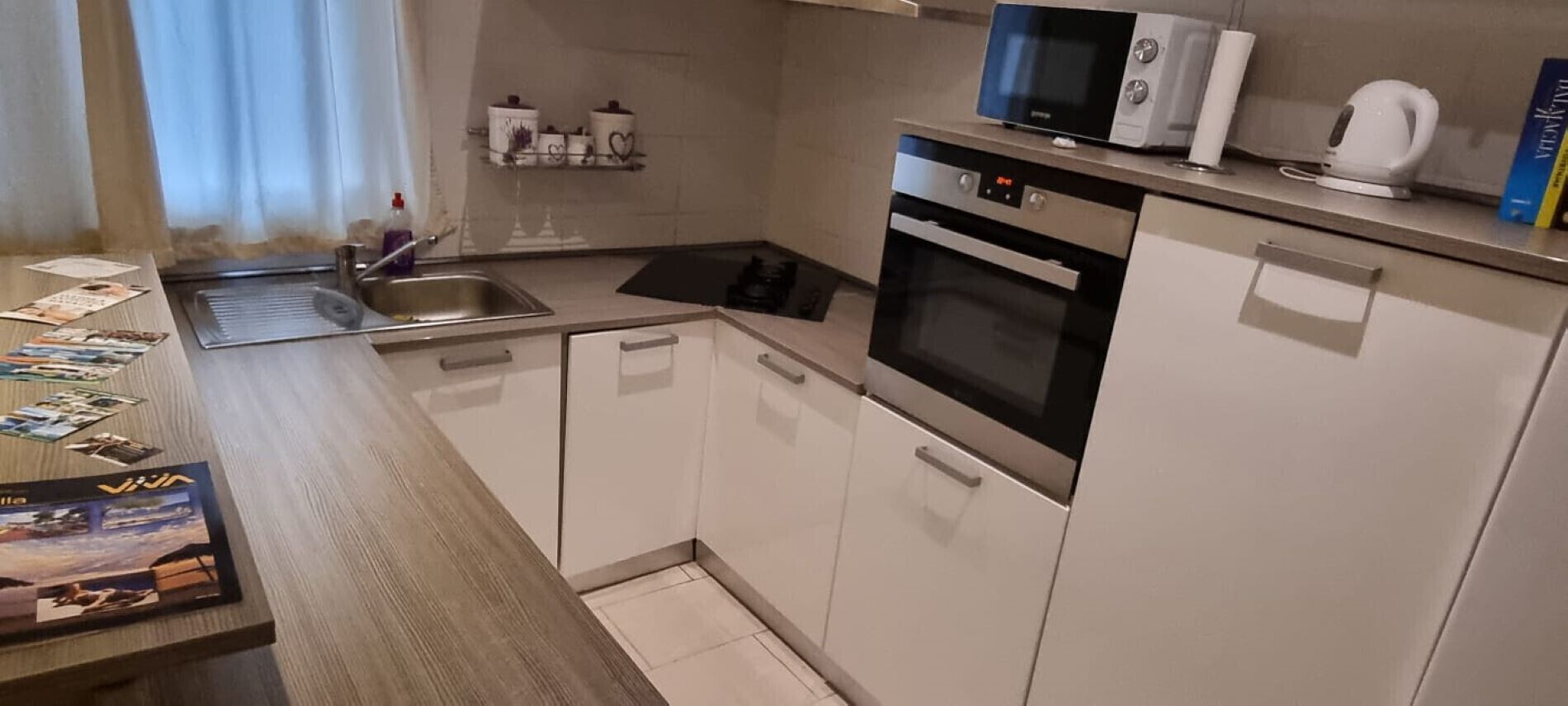 A compact kitchen with white cabinets, a microwave, an oven, and a sink.