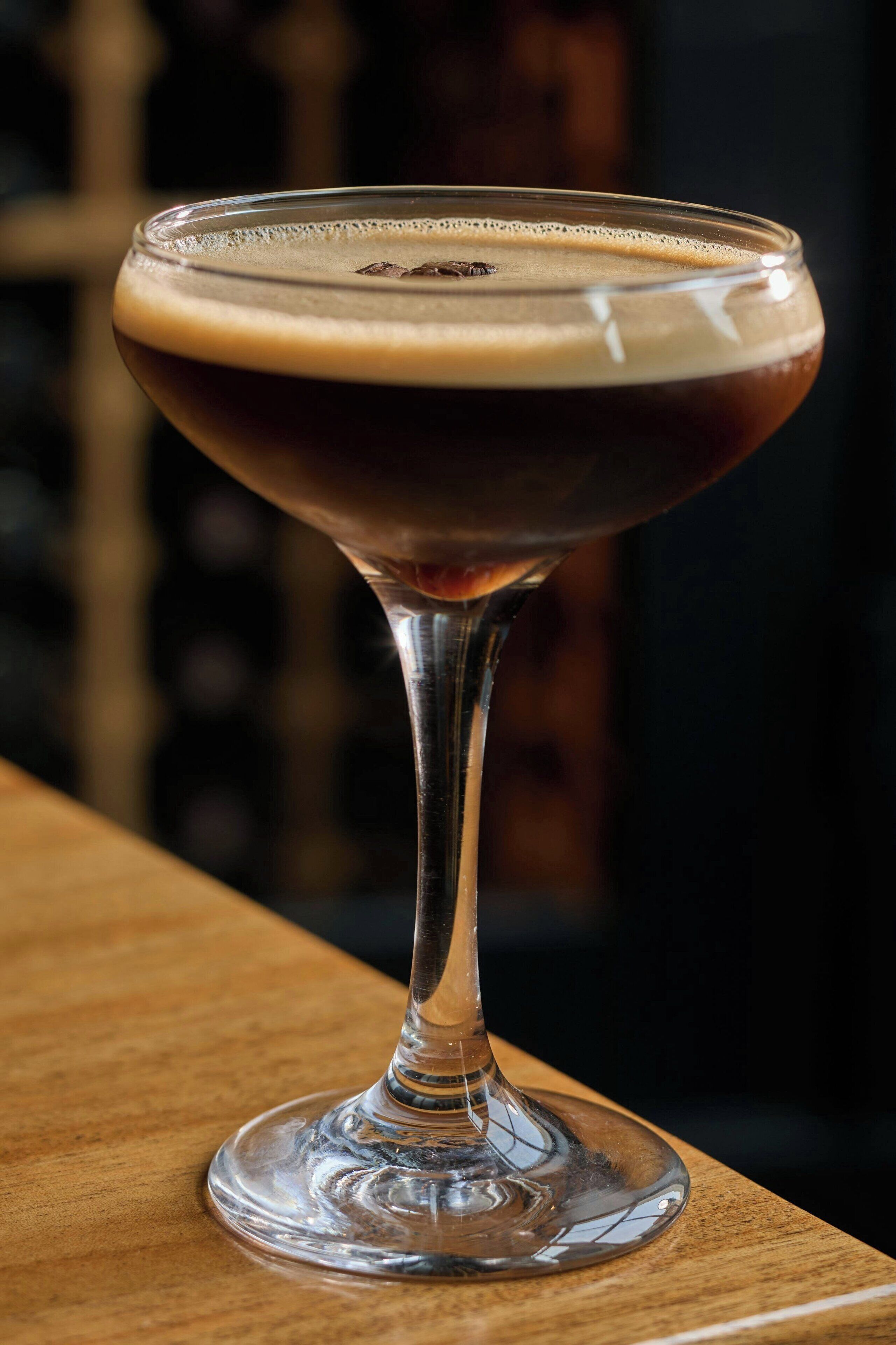 A cocktail in a stemmed glass on a wooden surface.