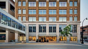 A hotel with a classic brick facade, large windows, and a modern glass entrance.