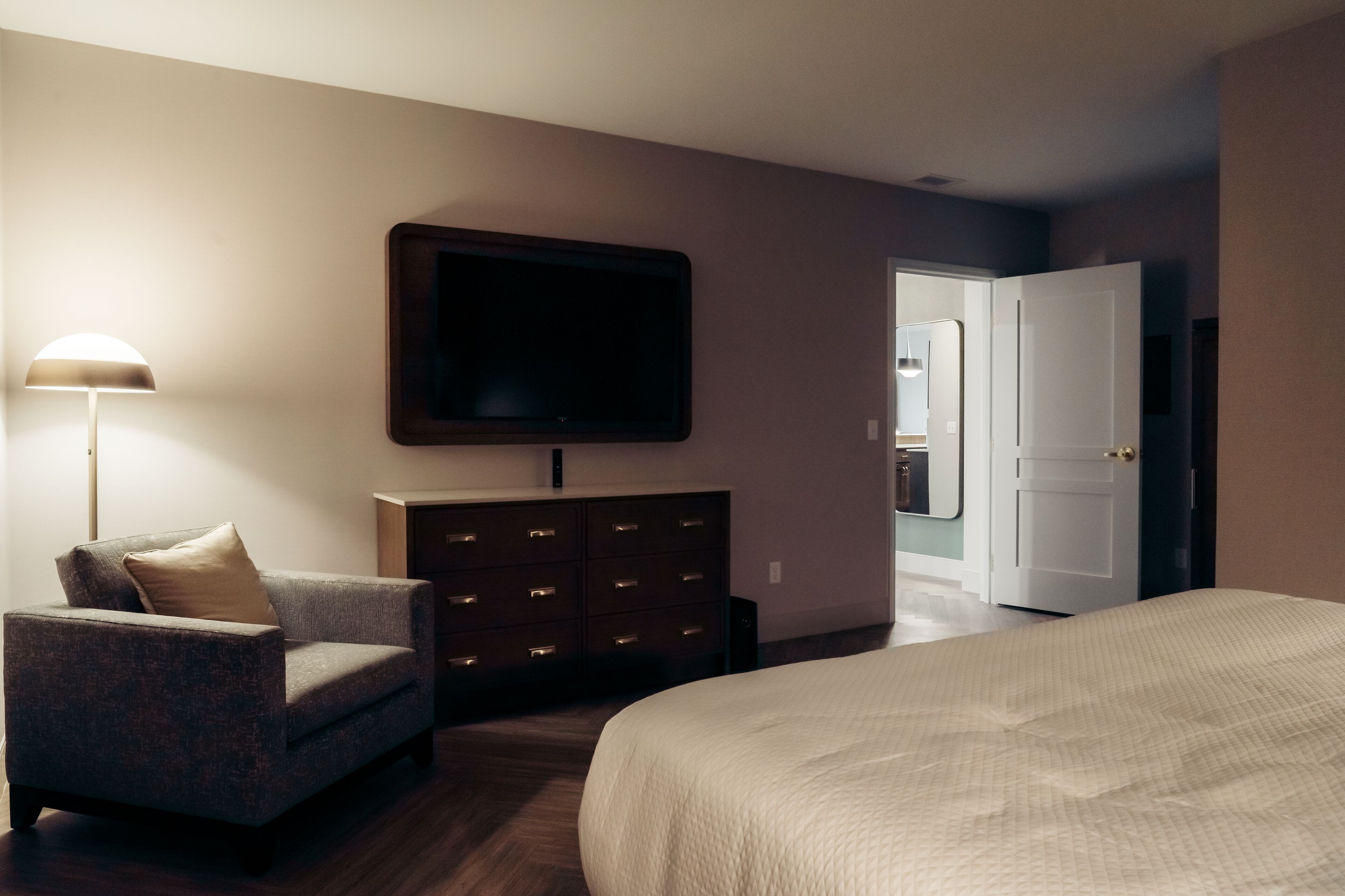 Ein Hotelzimmer mit Bett, Schminktisch, Fernseher und Lampe.