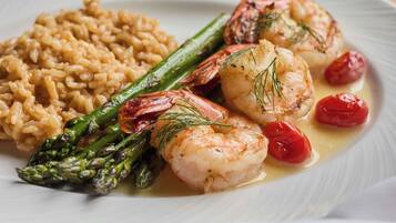 A plate of food with shrimp, asparagus, cherry tomatoes, and risotto.