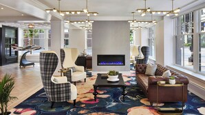 A spacious lobby with a fireplace, modern seating, and large windows.