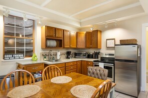 Una cocina con armarios de madera, un refrigerador de acero inoxidable, un microondas y una mesa de comedor con sillas.
