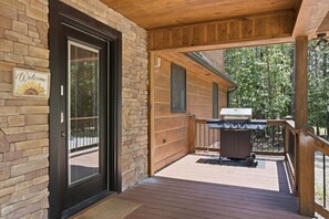 A wooden deck with a barbecue grill, a stone wall, and a welcome sign. - Sunrays - Hot Tub, Outdoor Fireplace & Game (Morganton)
