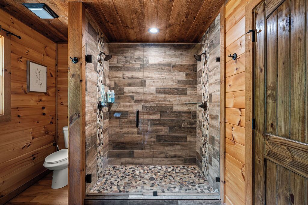 Un intérieur en bois comprenant un espace douche, des murs en bois et des toilettes.