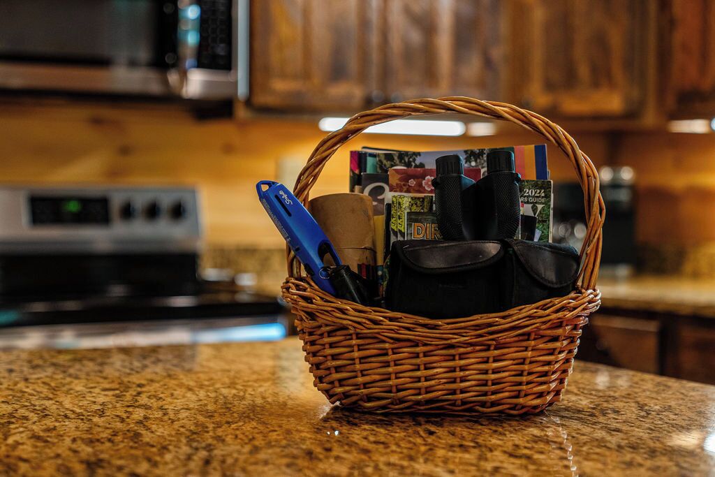 A wicker basket on a kitchen counter containing various kitchen utensils and a cookbook.