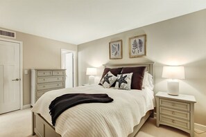 A bedroom with a bed, two nightstands, a dresser, and framed artwork on the wall. - Start Your Day with Oceanfront Magic! (Fernandina Beach)