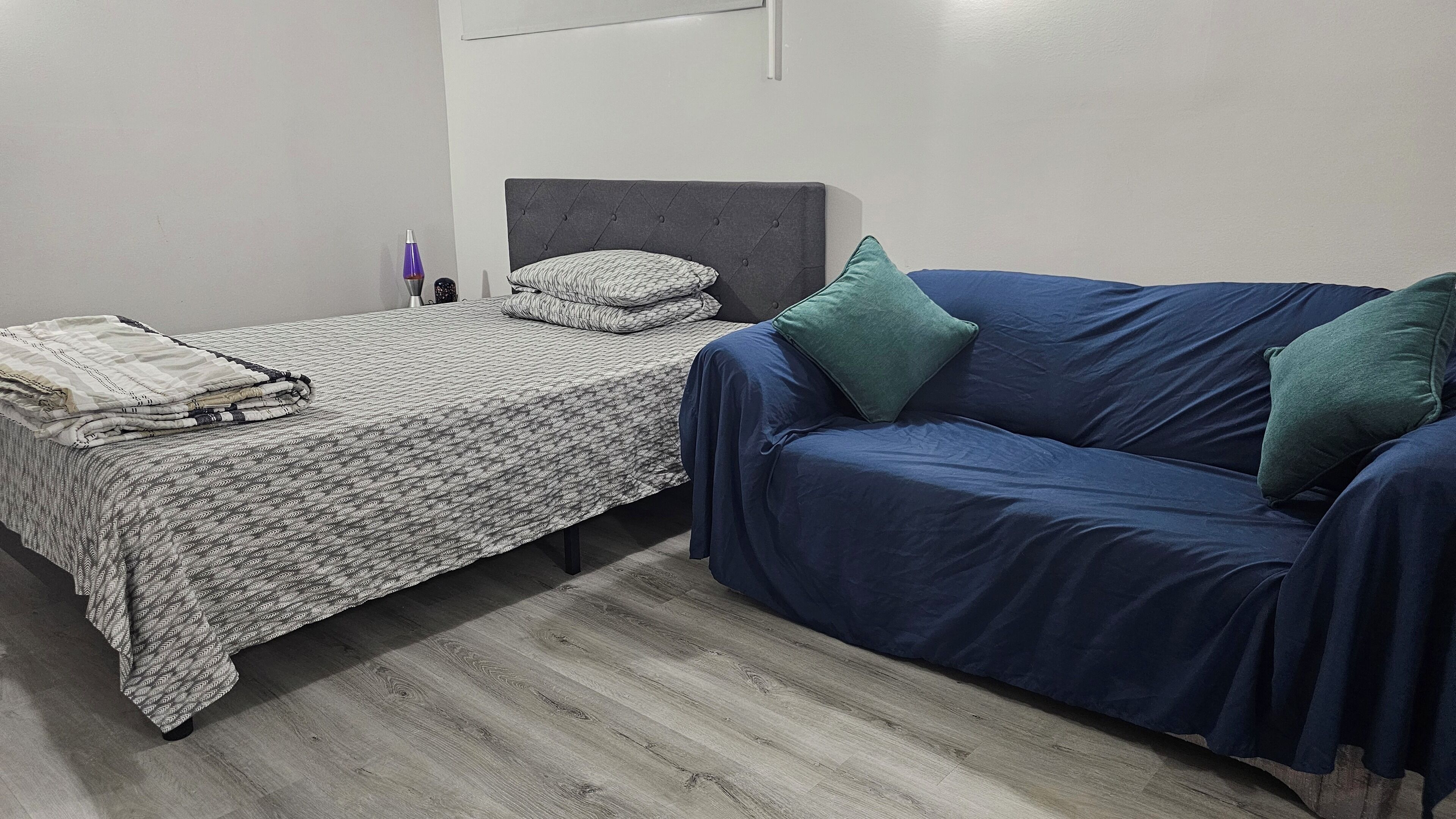 A bedroom with a bed and a blue sofa.