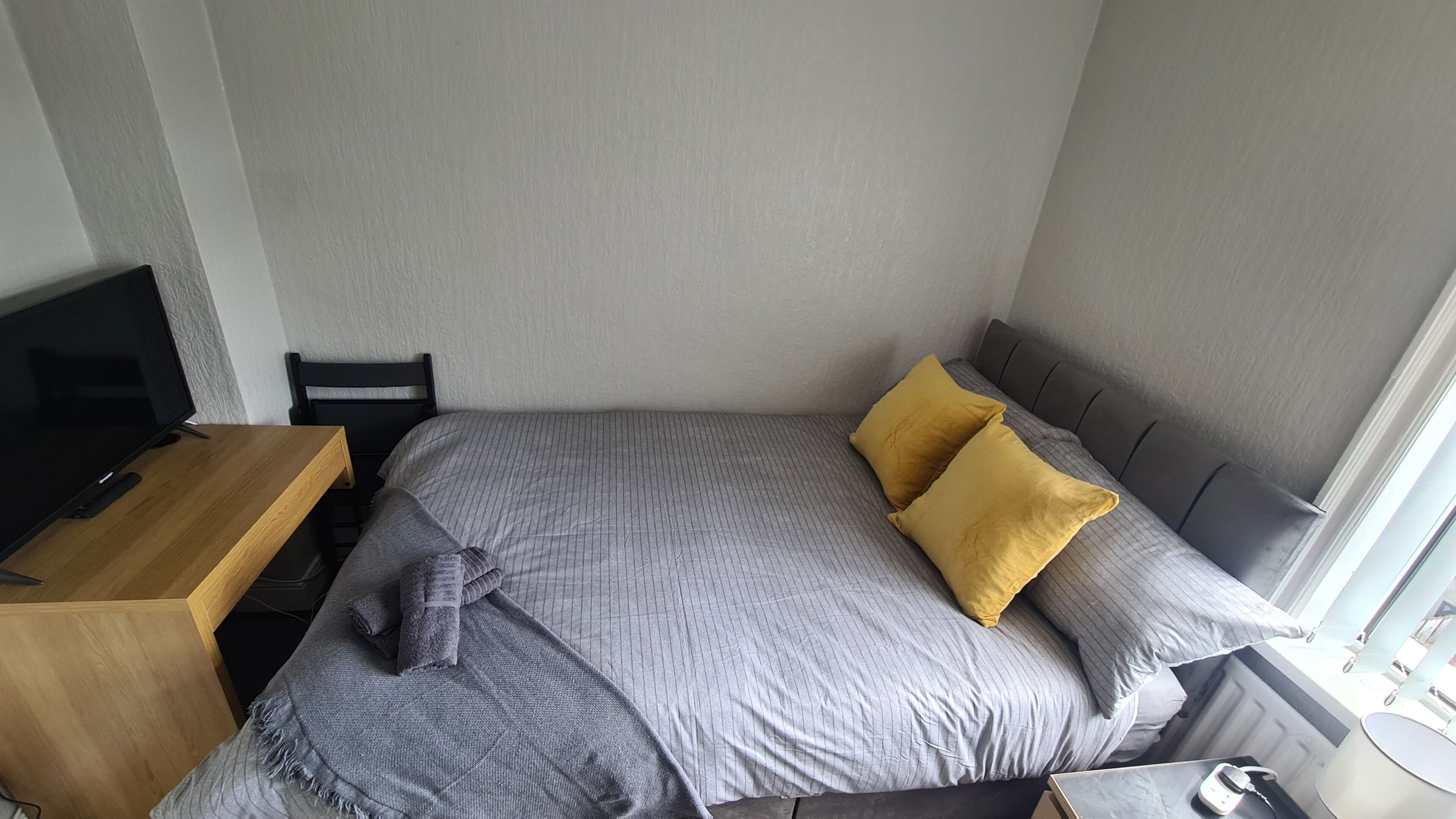 A bedroom with a bed, a TV, and a desk.